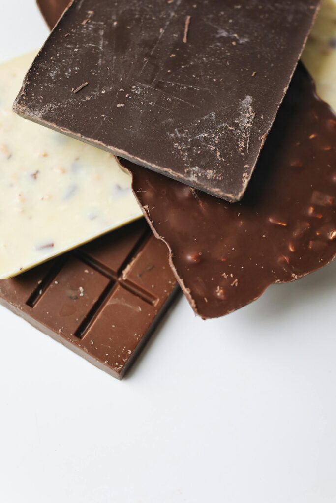 A stack of delectable dark, milk, and white chocolate bars on a white surface.